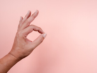 OK, hand sign gesture by man adult isolated on pastel pink background with copy space. Okay, agreement with middle-aged man fingers gesture.