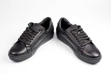 Black imitation leather shoes laced with wide laces. Close-up shot.