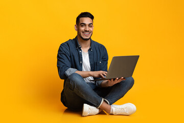 Happy young guy freelancer using modern laptop, programming