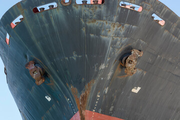 the bow of a cargo ship with a worn-out rusty hull.