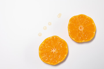 Split oranges against white background. Spilled juice drops visible