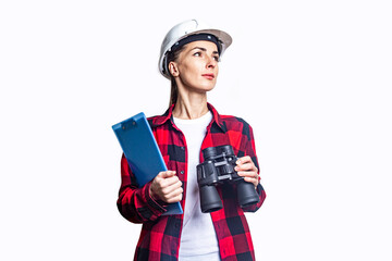 Young woman in construction clothes with a clipboard and binoculars on a light background.