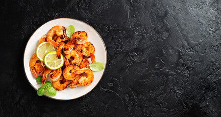 Grilled tiger shrimps with spice and lime. Black background. Top view, space for text.	