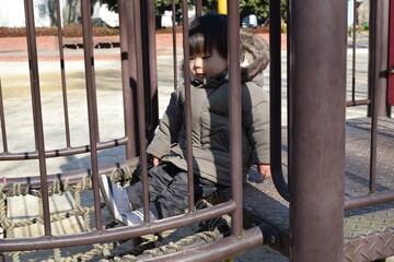 Fototapeta na wymiar 冬の公園の遊具で遊ぶ男の子　１歳８か月 