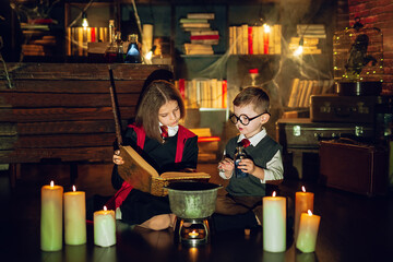 Obraz premium Little wizards read magic book and brew a potion . Halloween party. Cosplay Harry Potter