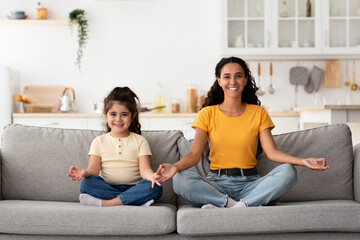 Fototapeta premium Wellness Concept. Beautiful Young Mother And Cute Little Daughter Meditating At Home