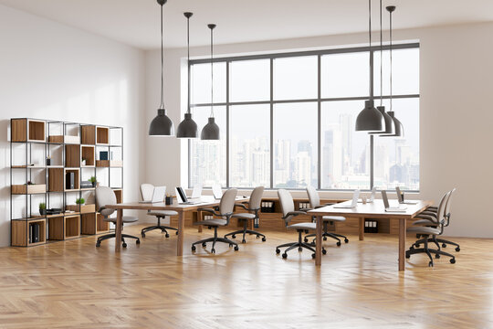 Light business room interior with seats, table with laptop, window with city view