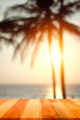 Wood plank with blurred sea and coconut tree background at sunset time. Concept of beach in summer.