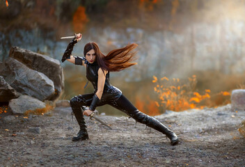 Fantasy fighting woman assassin actions in motion battle, hold daggers in hand. Red-haired girl...
