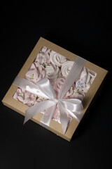 Homemade marshmallow in a gift box. Tied with a ribbon tied to a bow. On a black background.