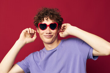 cute red-haired guy hand gestures heart shaped glasses posing red background