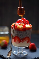 Dessert with chia, yogurt, bun, strawberry, pomegranate on a black background