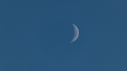 A new moon in a blue sky.