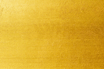 Gold wall texture background. Yellow shiny gold foil on concrete wall surface, vibrant golden luxury wallpaper