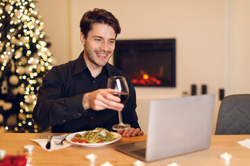 Excited man having dinner during virtual date on laptop