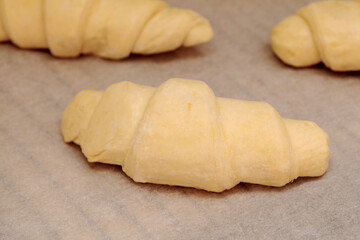 frozen raw croissants on a parchment covered oven grill tray