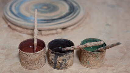 Three cans of red green and black mud paint with natural pigments