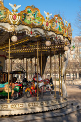 Fototapeta na wymiar Old French carousel in a Louvre park on a sunny winter day. Traditional fairground vintage carousel. Merry-go-round with horses. Paris, France.