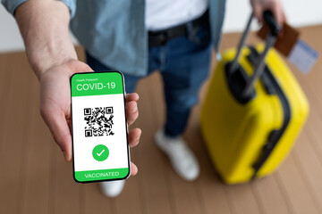 Digital green certificate. Male traveller holding phone with mobile app showing evidence of getting coronavirus jab - obrazy, fototapety, plakaty