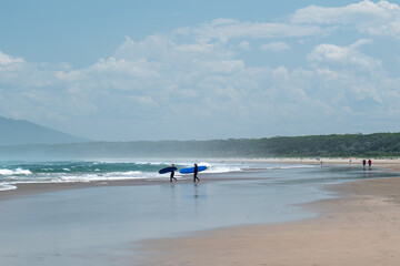 people walking down the beach with surfboards learning how to surf