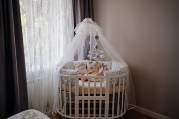 Fototapeta na wymiar a baby lies in a white crib with a canopy. furniture for the children's room.