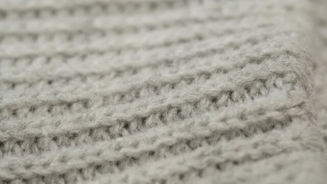 Grey knitted cloth, light gray woolen clothes fabric close-up, woven textile background.