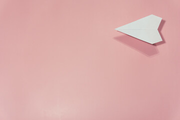 airplane made of white paper on a pink background