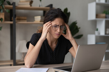 Stressed millennial latina hispanic woman in glasses looking at computer screen, stack with...