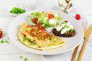 Breakfast. Omelette with tomatoes, cheese, green onions and sandwich with feta cheese.  Frittata - italian omelet.
