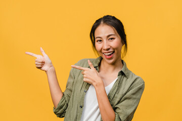 Portrait of young Asian lady smiling with cheerful expression, shows something amazing at blank...