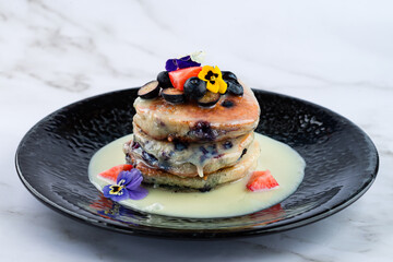 stack of pancakes with condensed milk and fresh berries