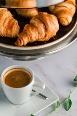 Breakfast with croissants, green leaves and black coffee composition