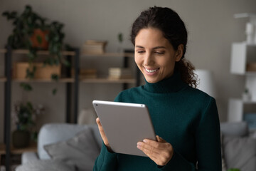 Happy millennial generation woman holding digital computer tablet in hands, involved in using...