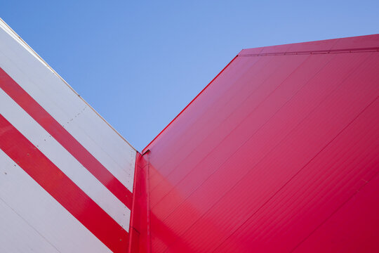 Low Angle View Of Modern Office Building with Red Facade against blue sky © alan