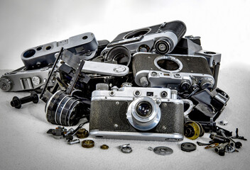 Old film camera on the background of broken and disassembled cameras