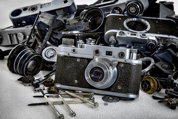 Old film camera on the background of broken and disassembled cameras