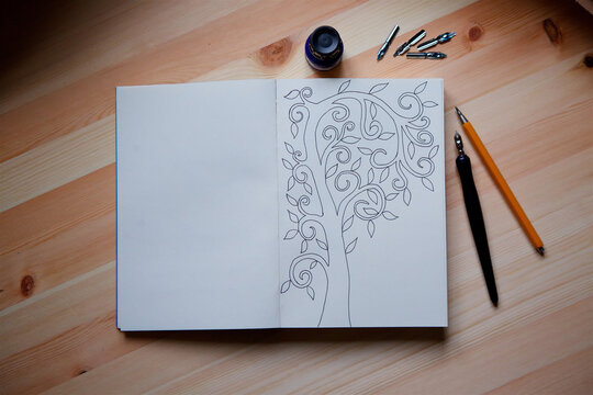 On the wooden surface is an open notebook with a sketch in the form of a tree with leaves.