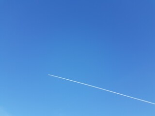 White airplane trail in blue sky