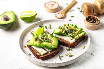 Healthy avocado toasts with rye bread, sliced avocado, cheese, pumpkin, nut and sesame for breakfast or lunch. Vegetarian food. Vegan menu. Food recipe background. Close up