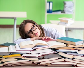 Young female student preparing for exams with many books