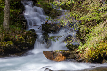 Natural water stream with small cascade waterfall and long exposure motion effect (Rohrmoos-Untertal, Austria)