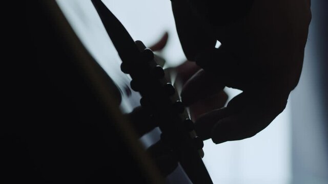 The musician plays the acoustic guitar. Closeup of the right hand. Macro shooting. Silhouette. Depth of field