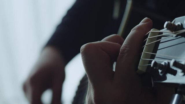 The musician plays the acoustic guitar. Closeup of the right hand. Macro shooting. Depth of field