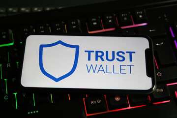 Viersen, Germany - January 9. 2022: Closeup of mobile phone with logo lettering of bitcoin trust wallet computer keyboard