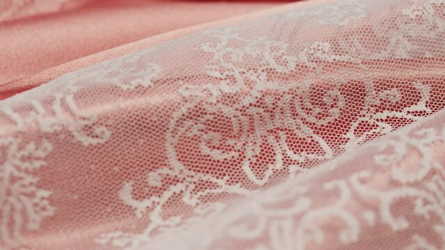 White lace on pink silk close-up, guipure texture and satin luxury cloth background. Luxurious design textile. Wedding dress. 