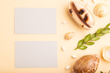 Composition of gray paper business cards, seashells, green boxwood. mockup on orange background. top view, copy space.