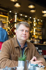 Portrait of an adult Caucasian male blonde in a beer bar resting after work.