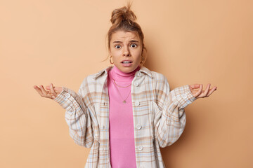 Confused hesitant young European woman shrugs shoulders and looks with bewilderment stands...