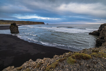 Picturesque autumn evening view to Reynisfjara ocean  black volcanic sand beach and rock formations from Dyrholaey Cape, Vik, South Iceland. Mount Reynisfjall on the background.