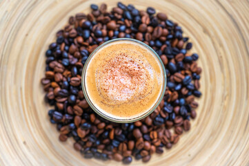 Leckerer Cappuccino mit Milchschaum und Schokostreuseln auf hölzernem Hintergrund mit Kaffeebohnen